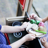 Child serving play food on a plate behind the PlanToys play centre