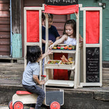 Children playing with the PlanToys play centre made into a fresh market shop. 
