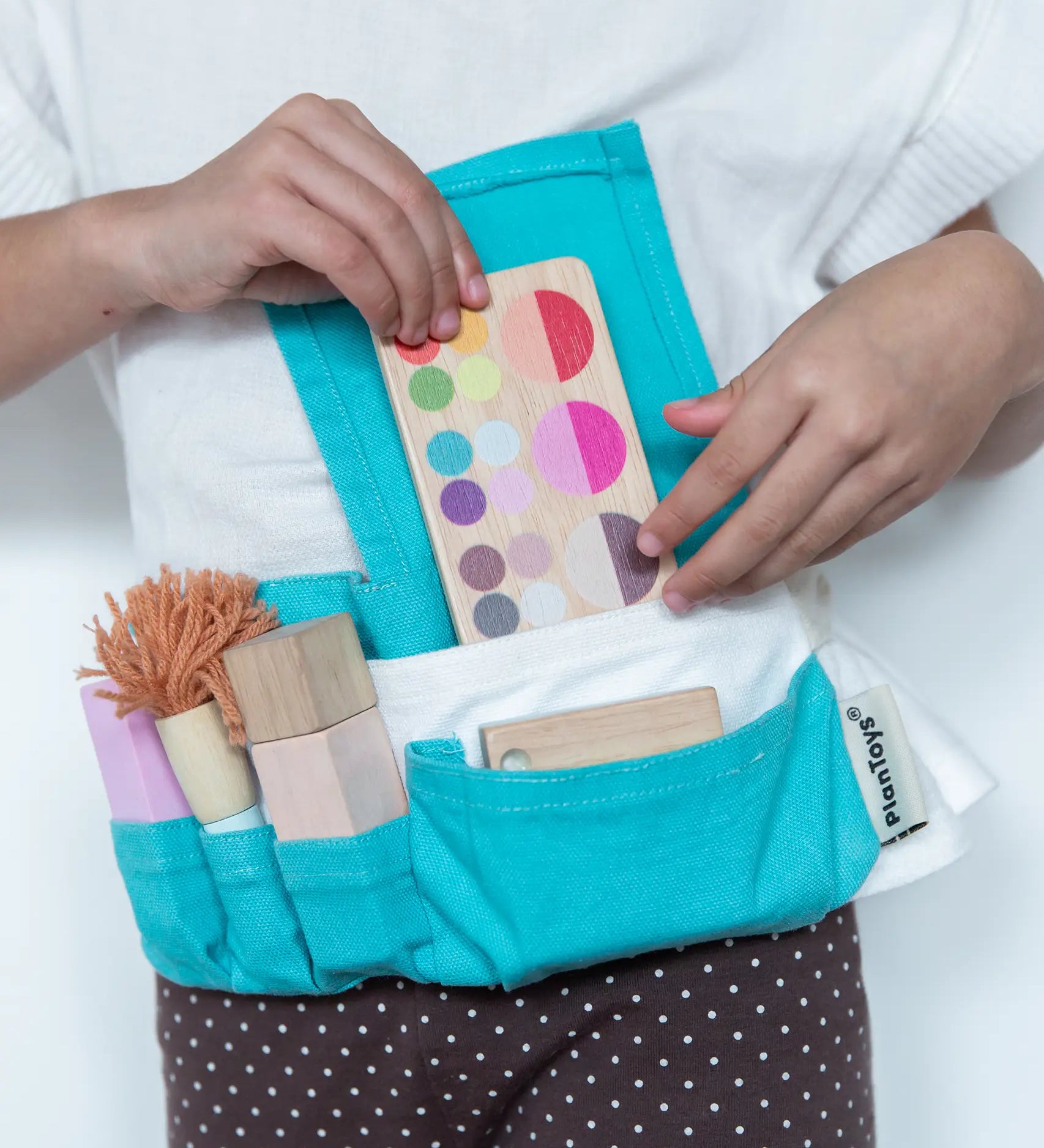 Child wearing the blue waist bag filled with tools and accessories from the PlanToys make up set