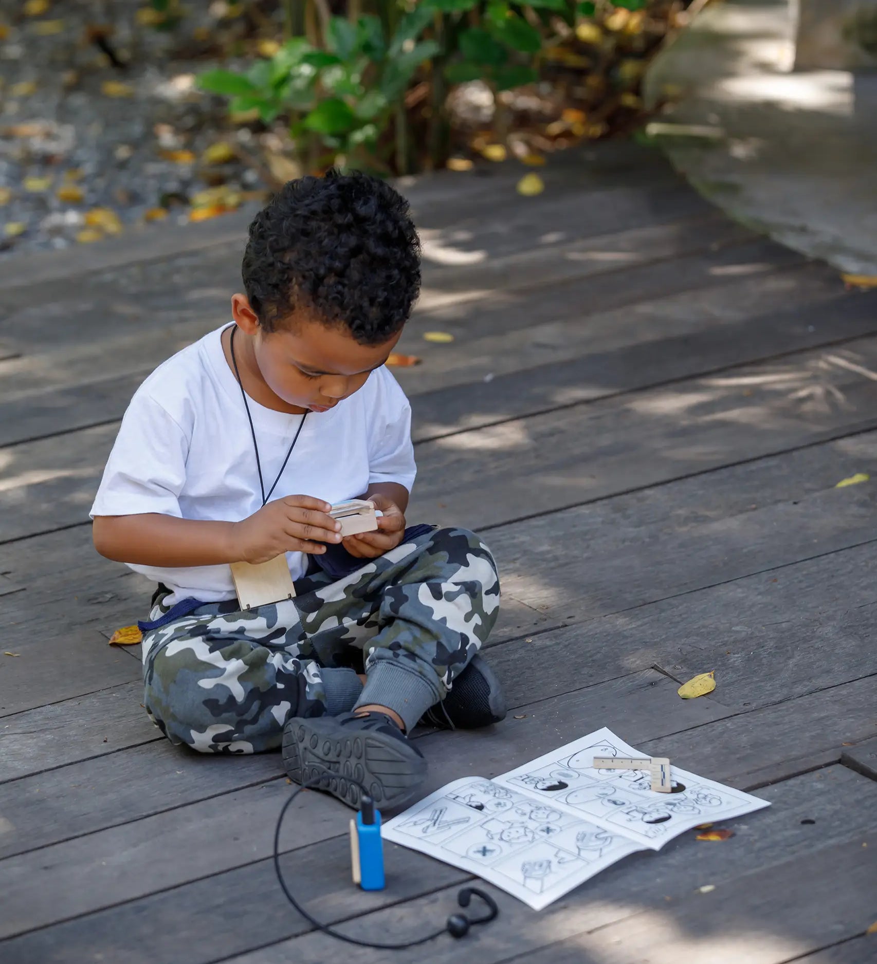 Child playing with the PlanToys secret agent play set on a wooden surface