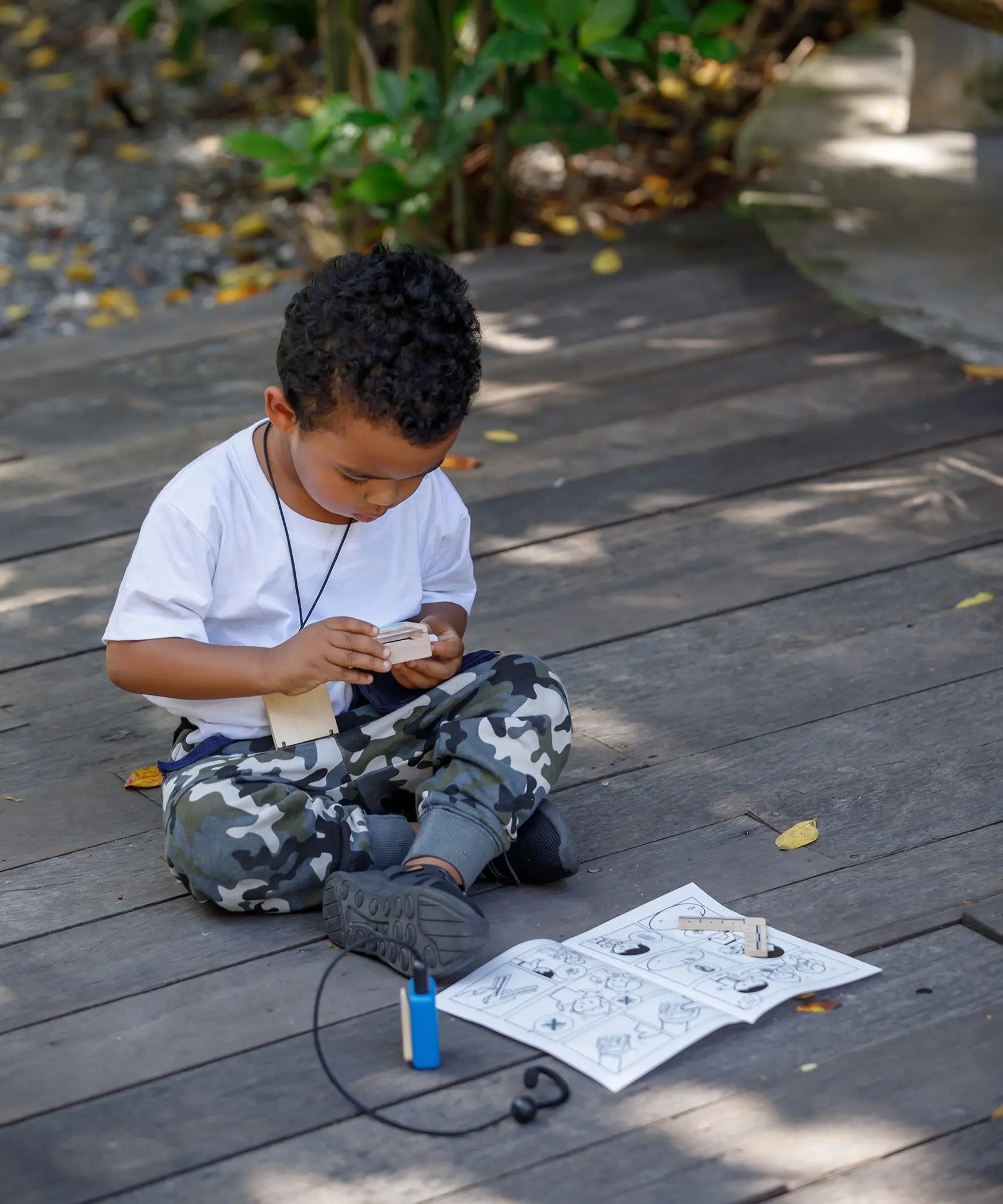Child playing with the PlanToys secret agent play set on a wooden surface