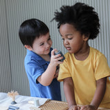 Child holding a wooden spray bottle from the PlanToys shaving play set showing scale
