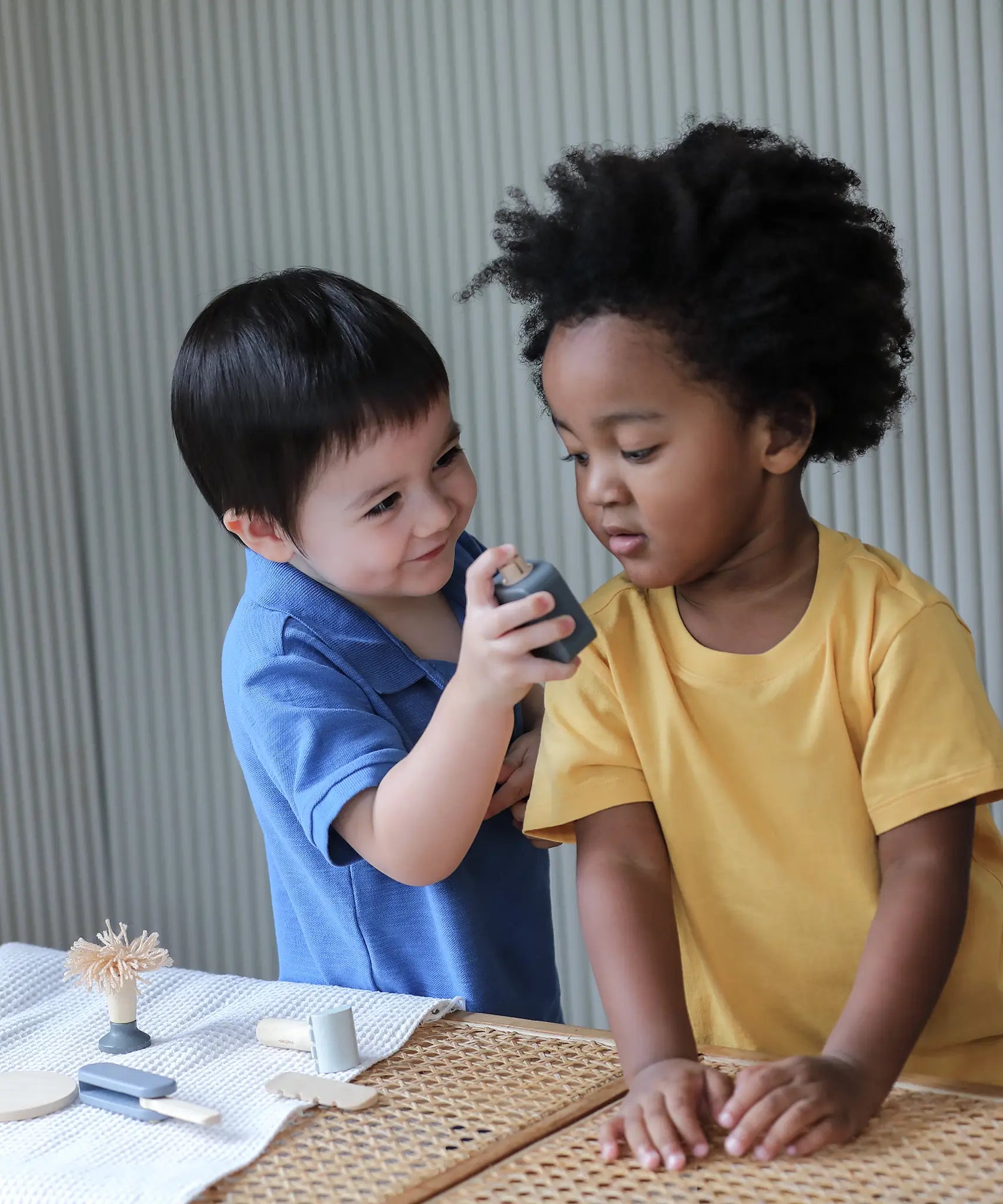 Child holding a wooden spray bottle from the PlanToys shaving play set showing scale