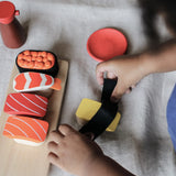 Child playing with the PlanToys wooden sushi play set on a white sheet