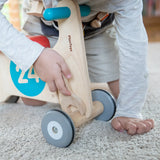Child using the wooden spanner on a bike from the PlanToys tool play belt set 
