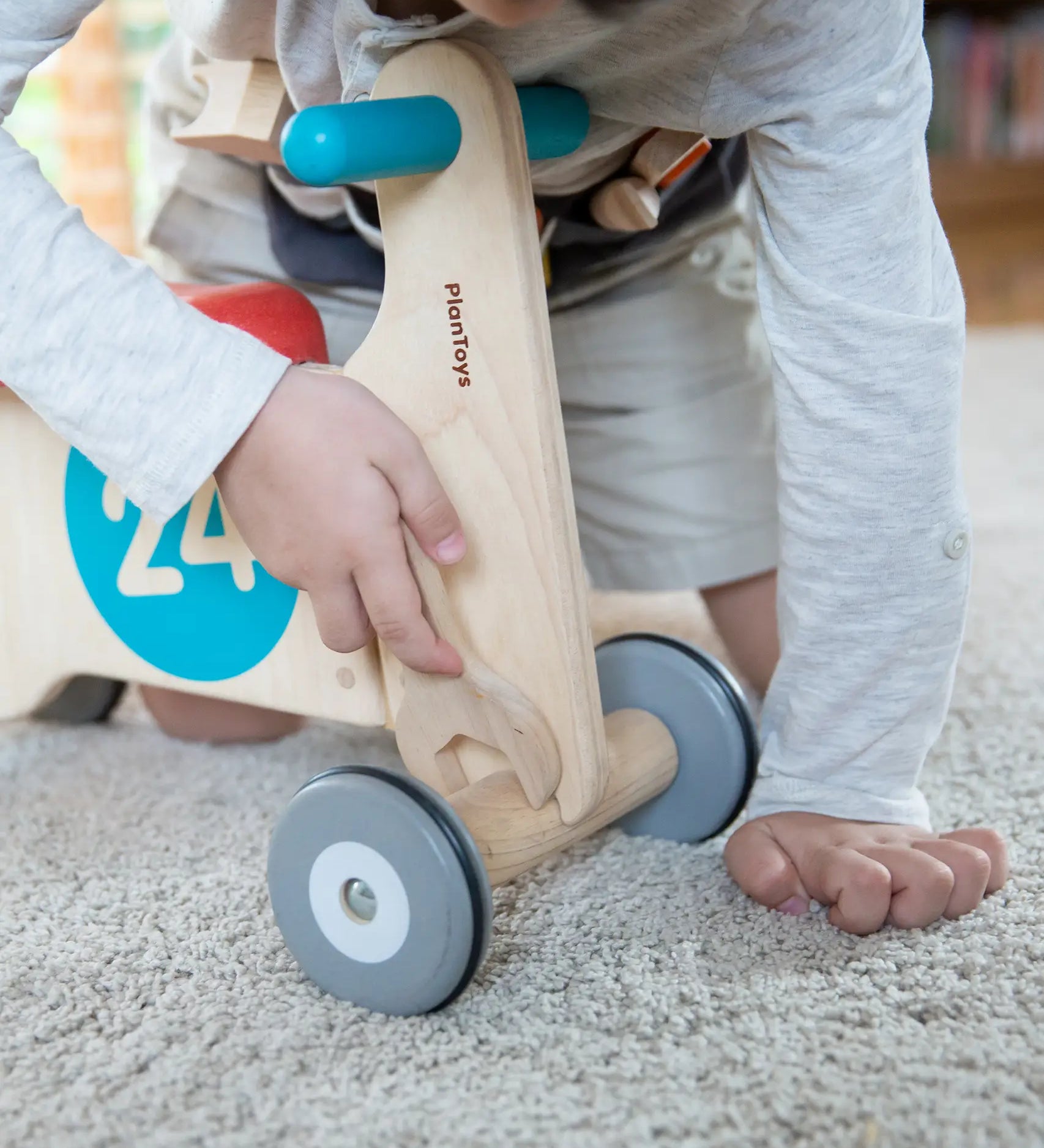 Child using the wooden spanner on a bike from the PlanToys tool play belt set 