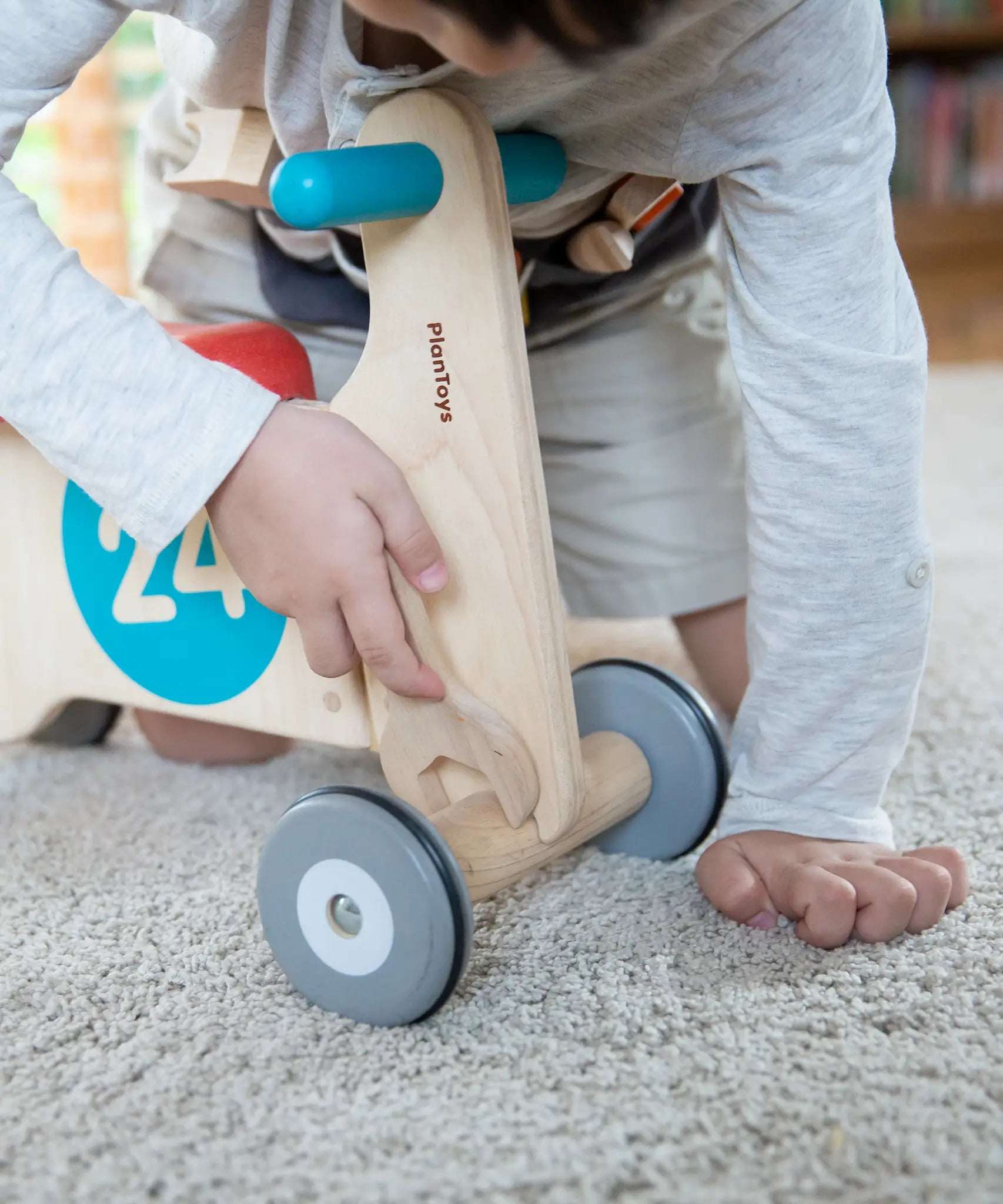 Child using the wooden spanner on a bike from the PlanToys tool play belt set 