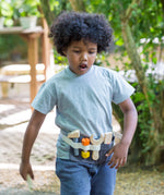 Child wearing a PlanToys tool waist play belt in the garden