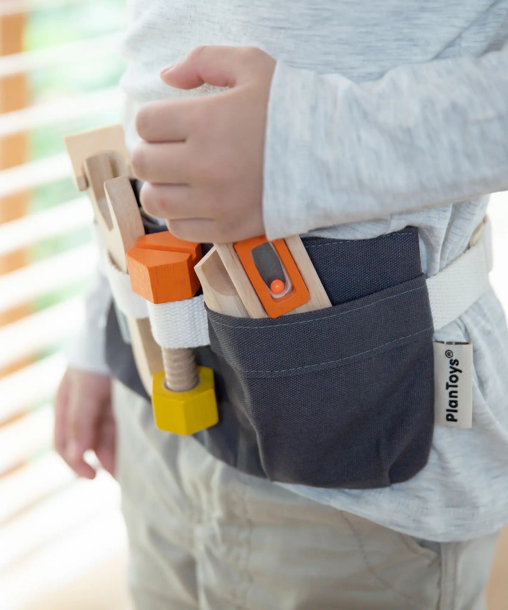 PlanToys tool belt play set showing different tools pockets, worn by a child