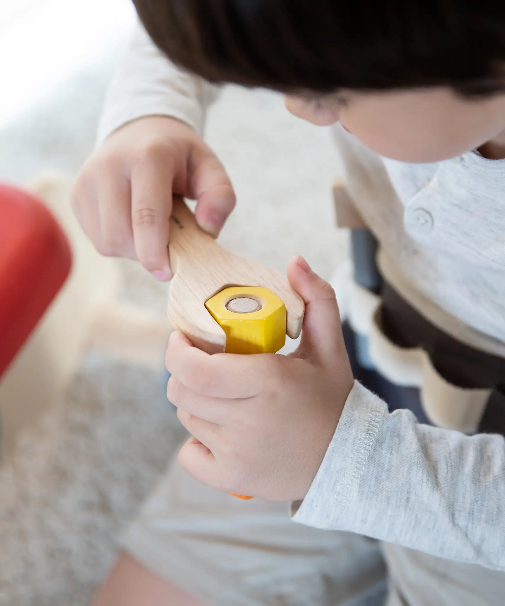 Child using the wooden spanner on a bolt  from the PlanToys tool play belt set 