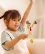Child playing with the PlanToys Weightlifting Acrobat wooden toy.