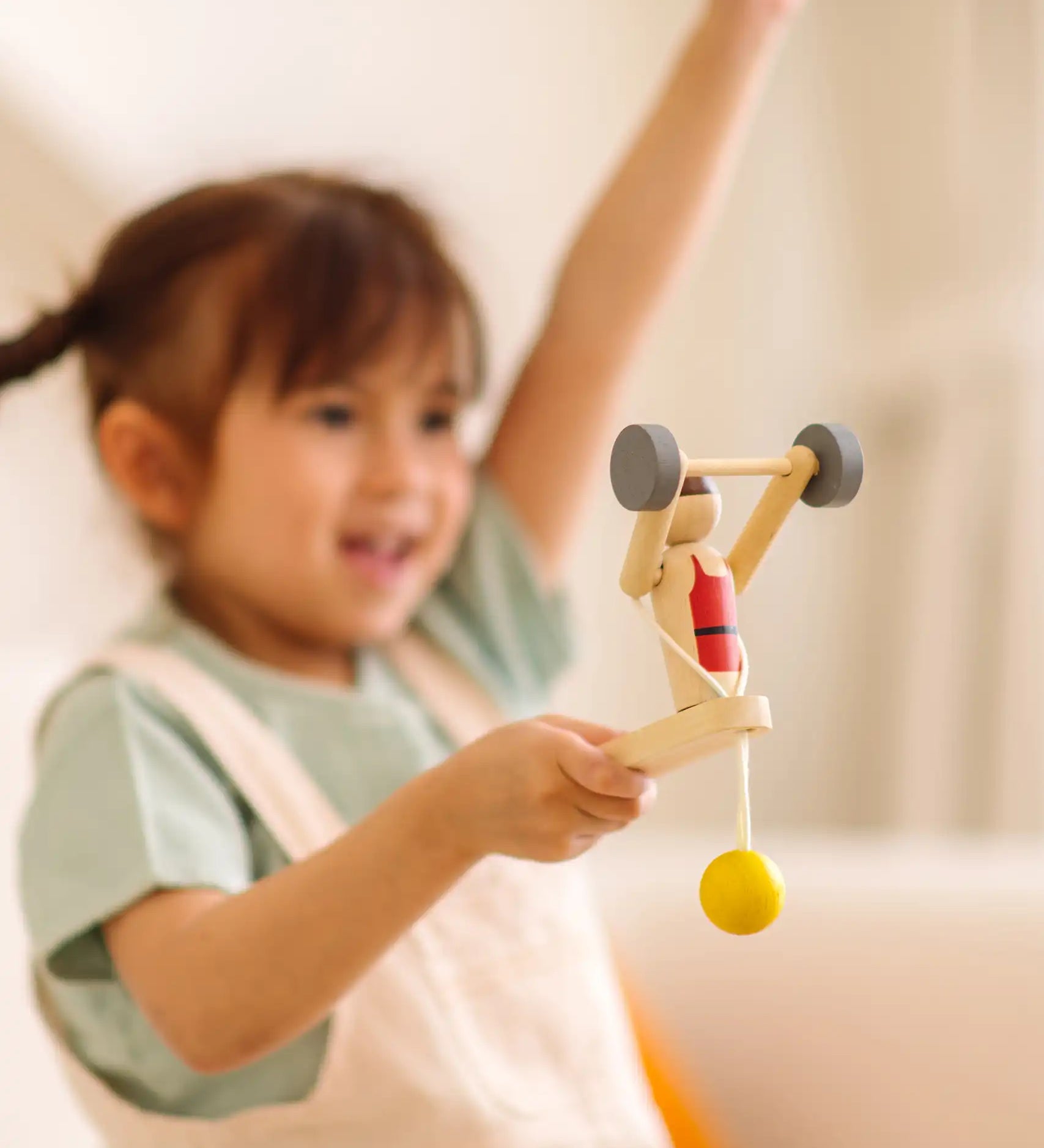 Child playing with the PlanToys Weightlifting Acrobat wooden toy.