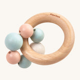 PlanToys Pastel Beads Rattle is a beautifully crafted, wooden baby rattle that is perfect for teething and sore gums. The rattle comes with a wooden ring, and attached to the ring a pastel pink, blue and white beads. The image is on a cream background
