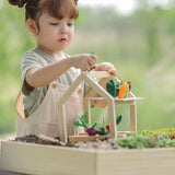 Child sorting different veg pieces on the  planters and shelf pieces in the PlanToys wooden blooming greenhouse 
