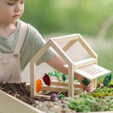 Child removing a veg piece from the planter inside the PlanToys wooden blooming greenhouse 