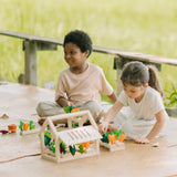 Children sorting extra veg pieces on planters included with the PlanToys wooden blooming greenhouse 