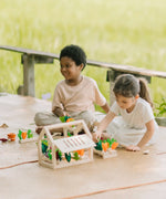 Children sorting extra veg pieces on planters included with the PlanToys wooden blooming greenhouse 