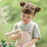 Child dismantling planting beds from the PlanToys stack & sprout set with loose veg pieces