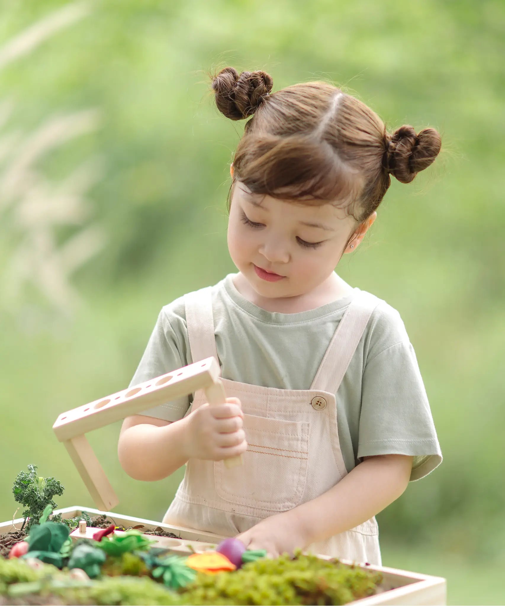 Child dismantling planting beds from the PlanToys stack & sprout set with loose veg pieces