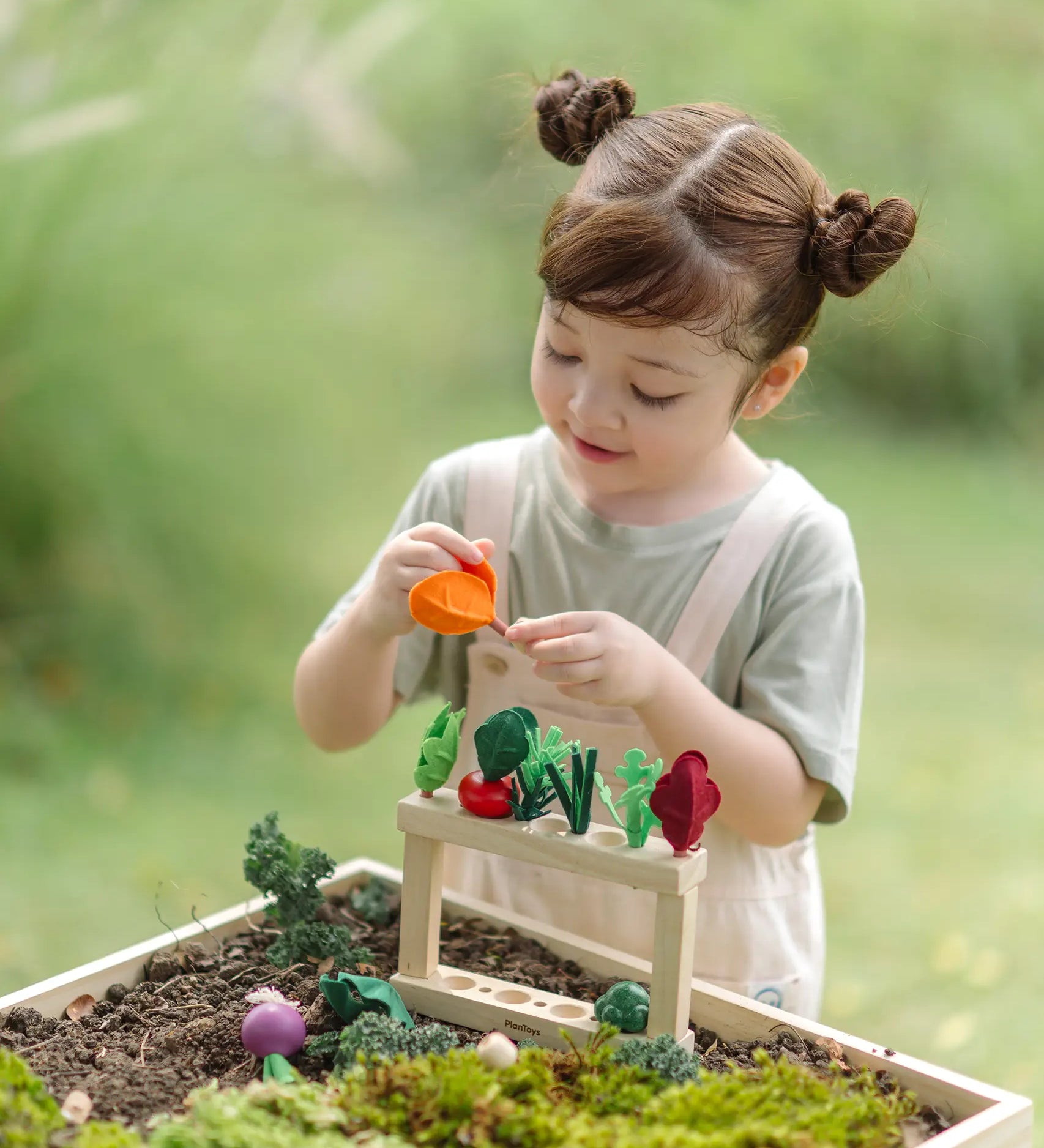 Child sorting different pieces on the PlanToys stack and sprout set on a large planter