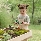 Child standing next to stacked planting beds from the PlanToys stack & sprout set with loose veg sitting on top in a garden