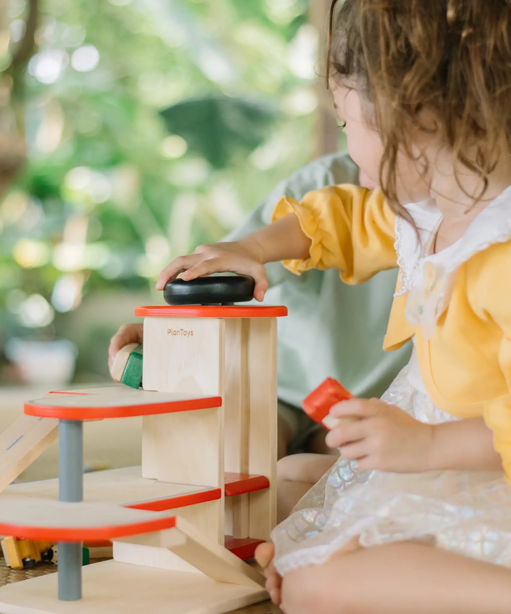 Child using the wind up lift on the PlanToys wooden city parking garage. 