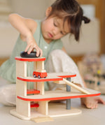 Child playing with the PlanToys wooden city parking garage using the wind up vehicle working lift