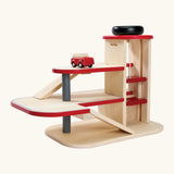 PlanToys wooden city parking garage. Features 3 levels with ramps, a wind up working lift and a vehicle