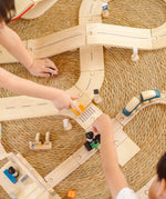 Overhead view of children playing with the PlanToys wooden city transit rail and road playset