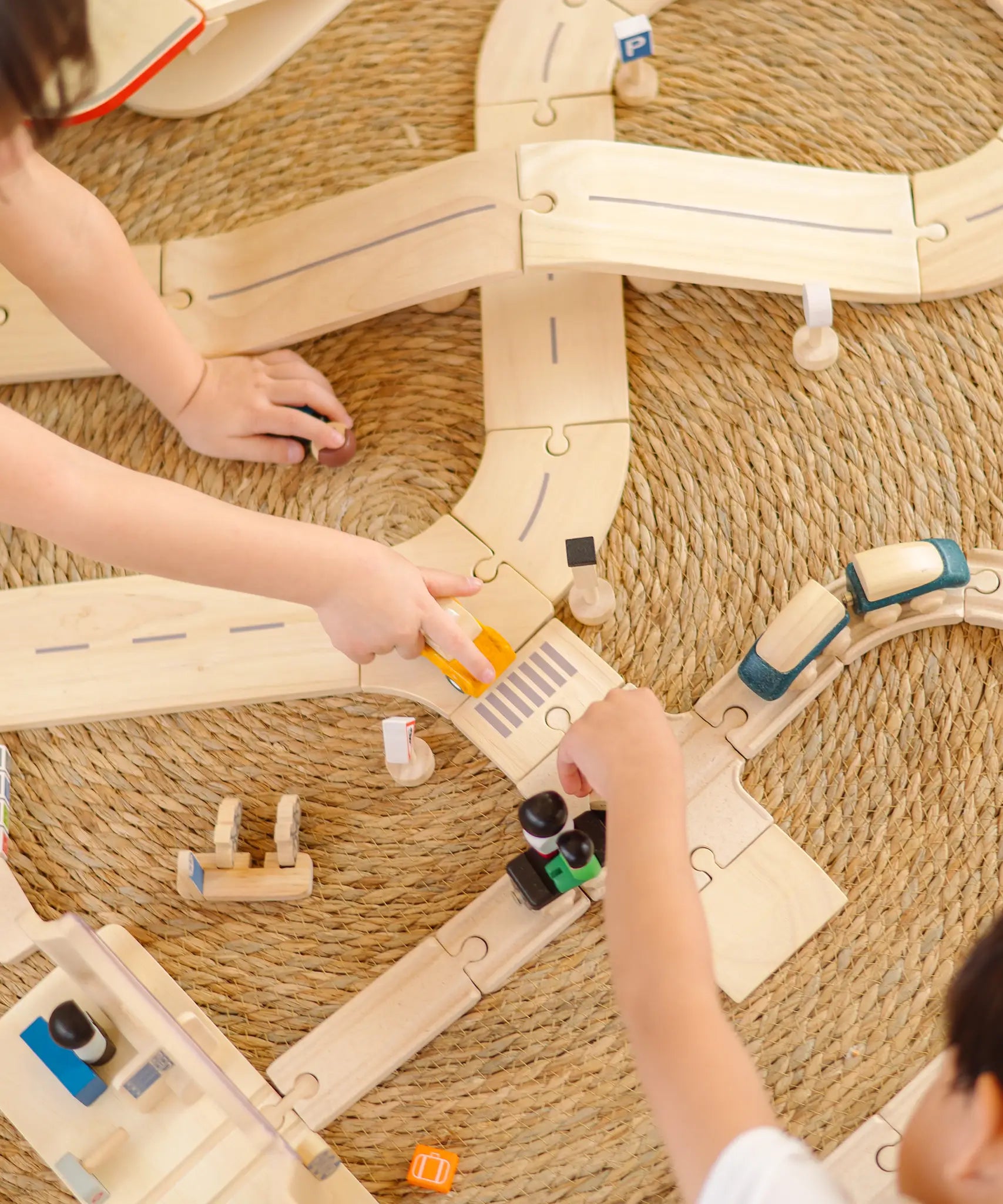 Overhead view of children playing with the PlanToys wooden city transit rail and road playset