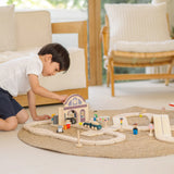 Child playing with the PlanToys station section of a city transit rail road playset