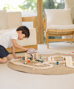 Child playing with the PlanToys station section of a city transit rail road playset