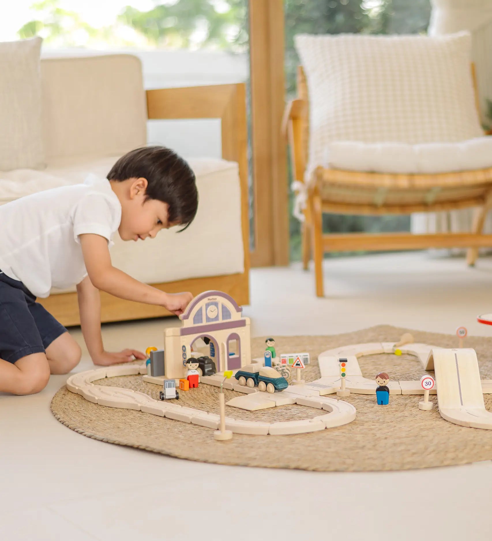 Child playing with the PlanToys station section of a city transit rail road playset