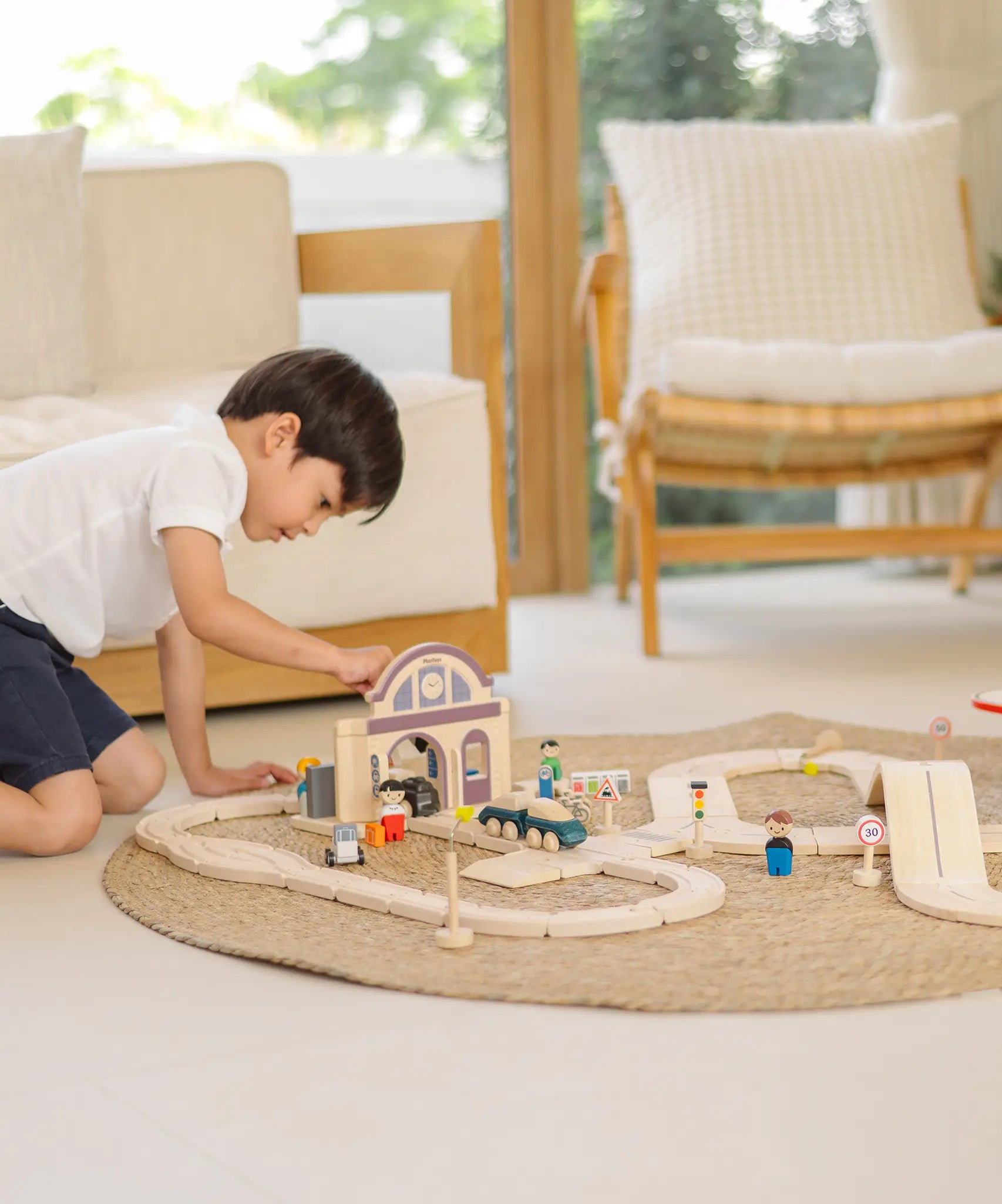 Child playing with the PlanToys station section of a city transit rail road playset