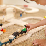 Child playing with wooden trains with magnetic connectors from the PlanToys city transit rail and road playset
