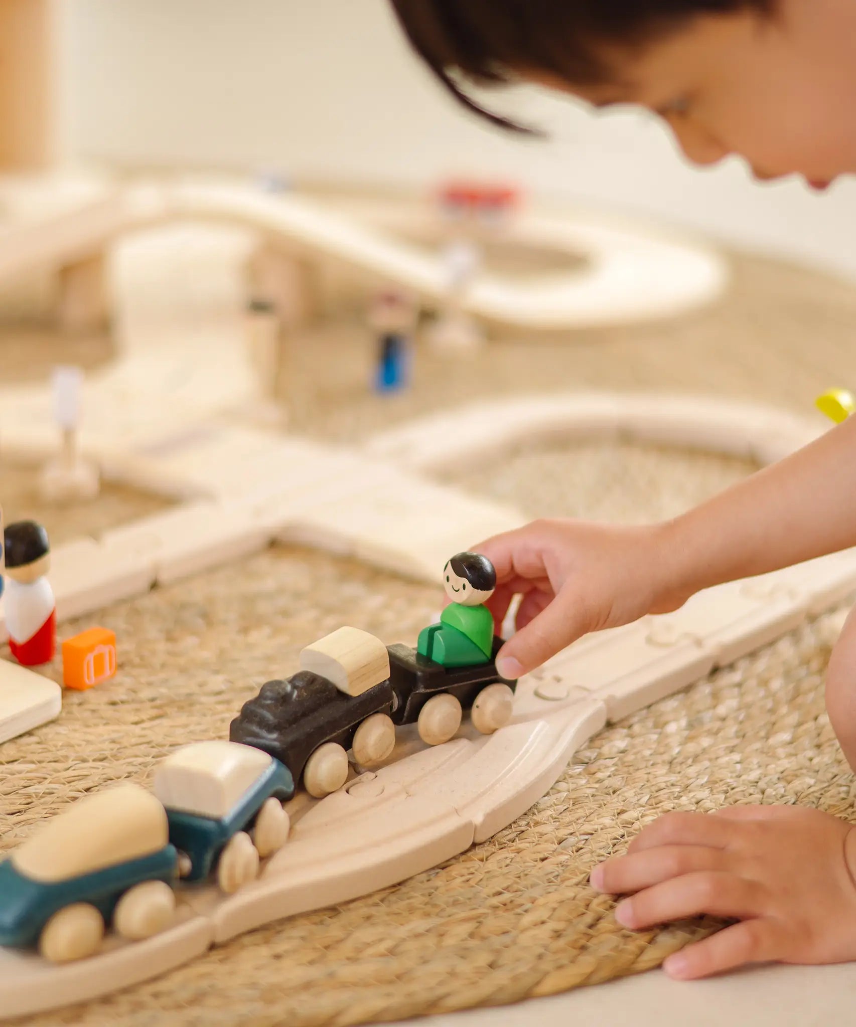 Child playing with wooden trains with magnetic connectors from the PlanToys city transit rail and road playset