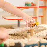 Child playing with a yellow truck on a PlanToys city transit rail and road playset