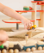 Child playing with a yellow truck on a PlanToys city transit rail and road playset