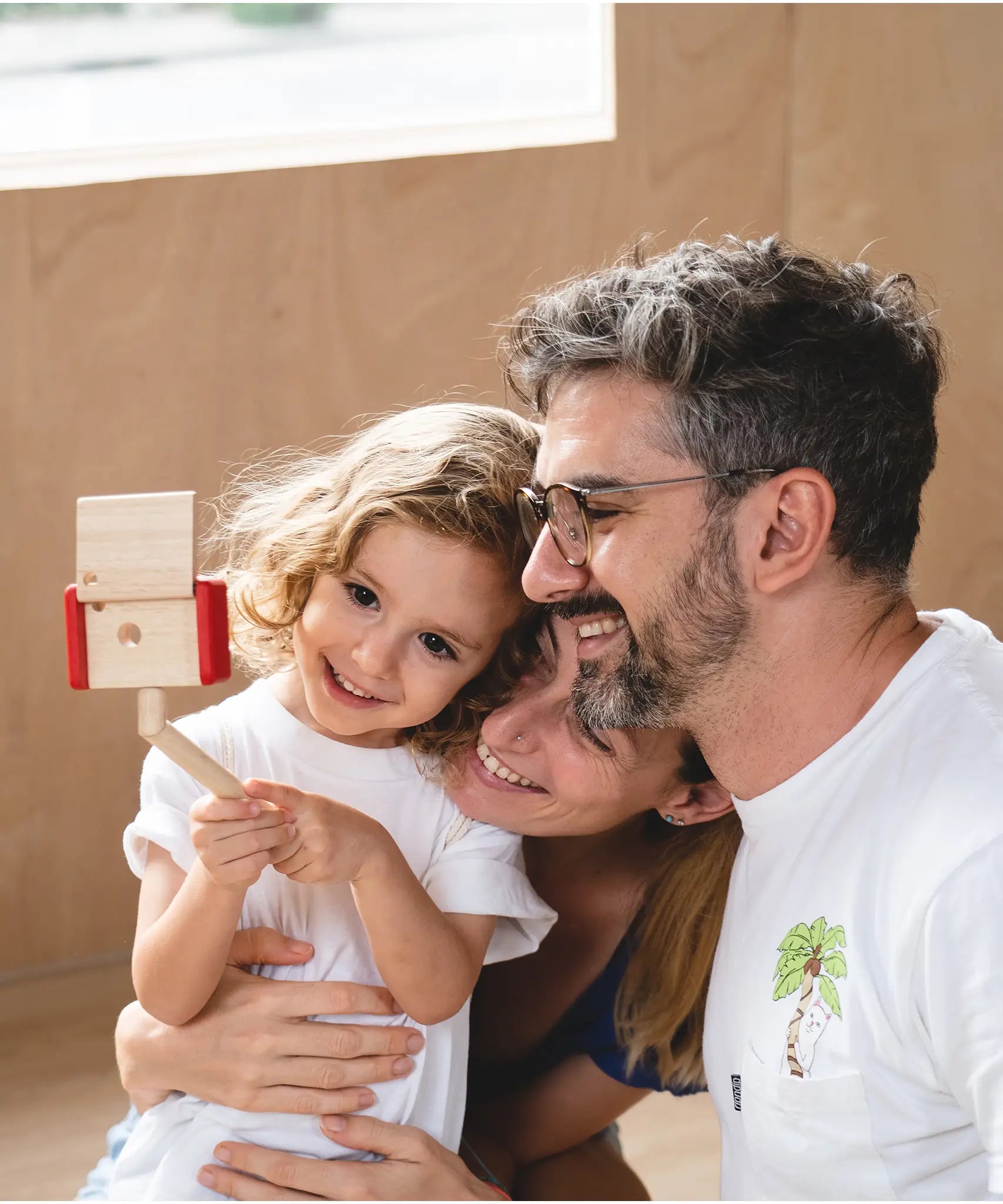 Child holding a seflie stick with a camera from the PlanToys vlogger kit taking a family selfie