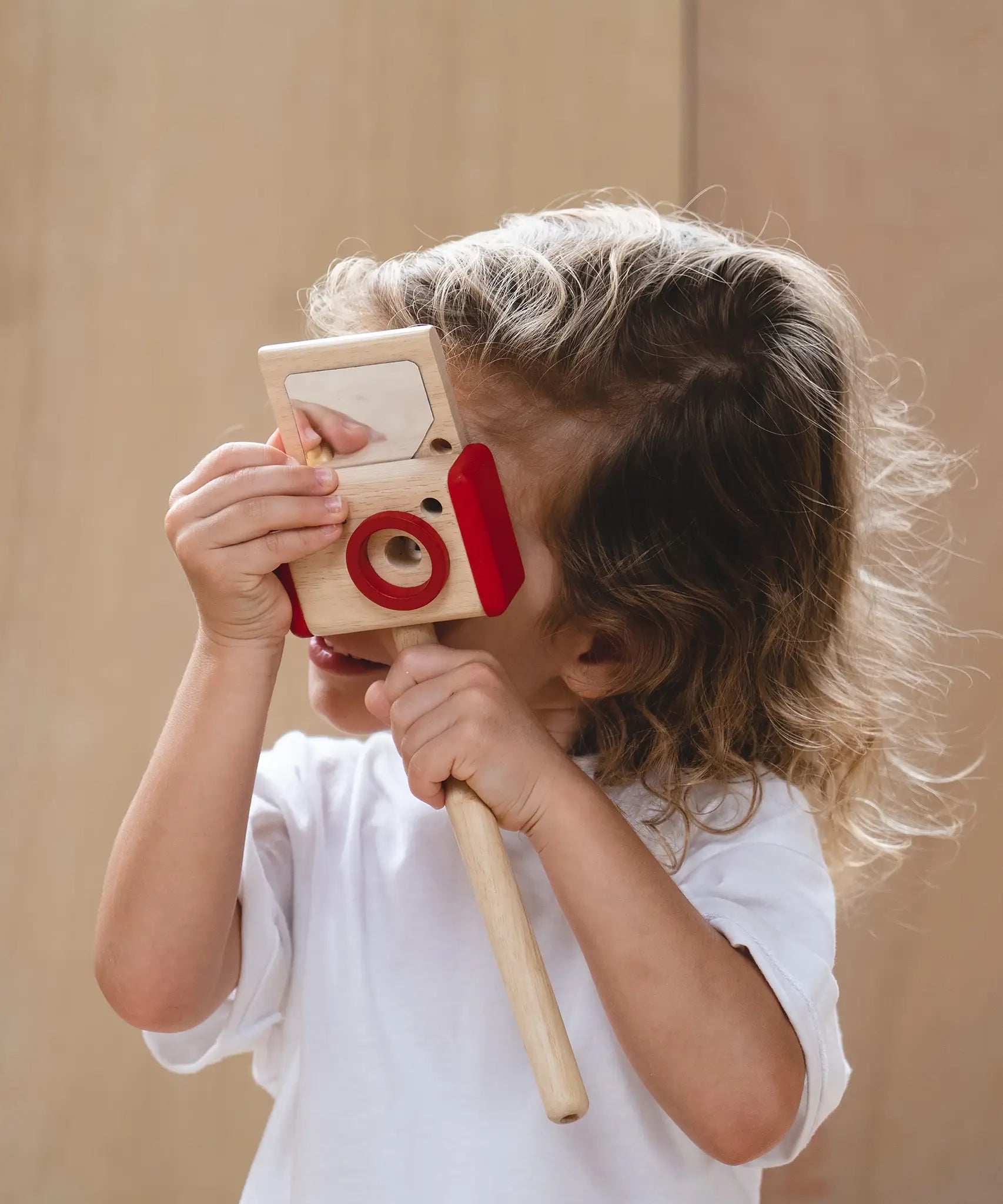 Child looking through a camera from the PlanToys vlogger kit