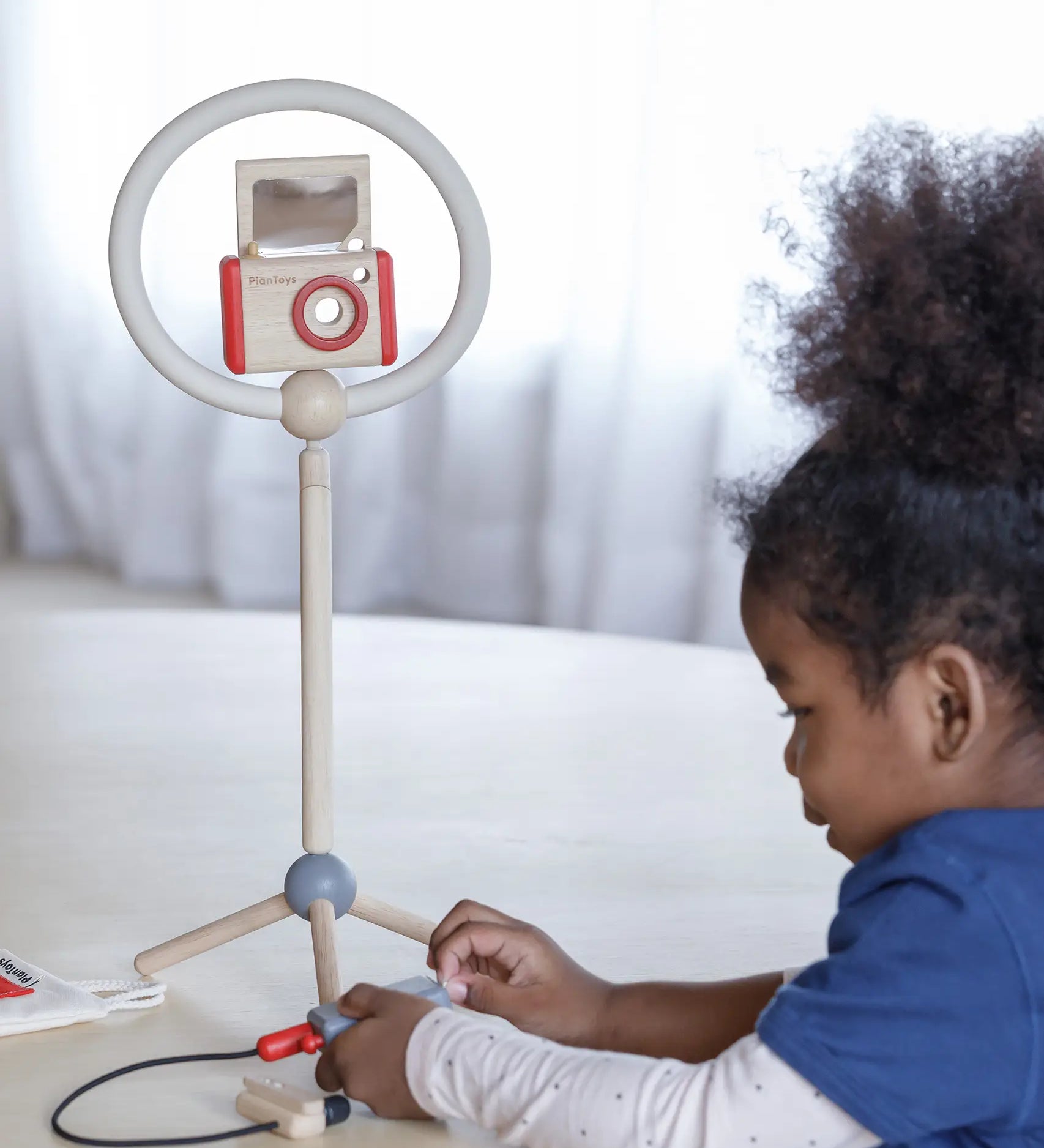 Child setting up the ring light and camera from the PlanToys pretend vlogger kit