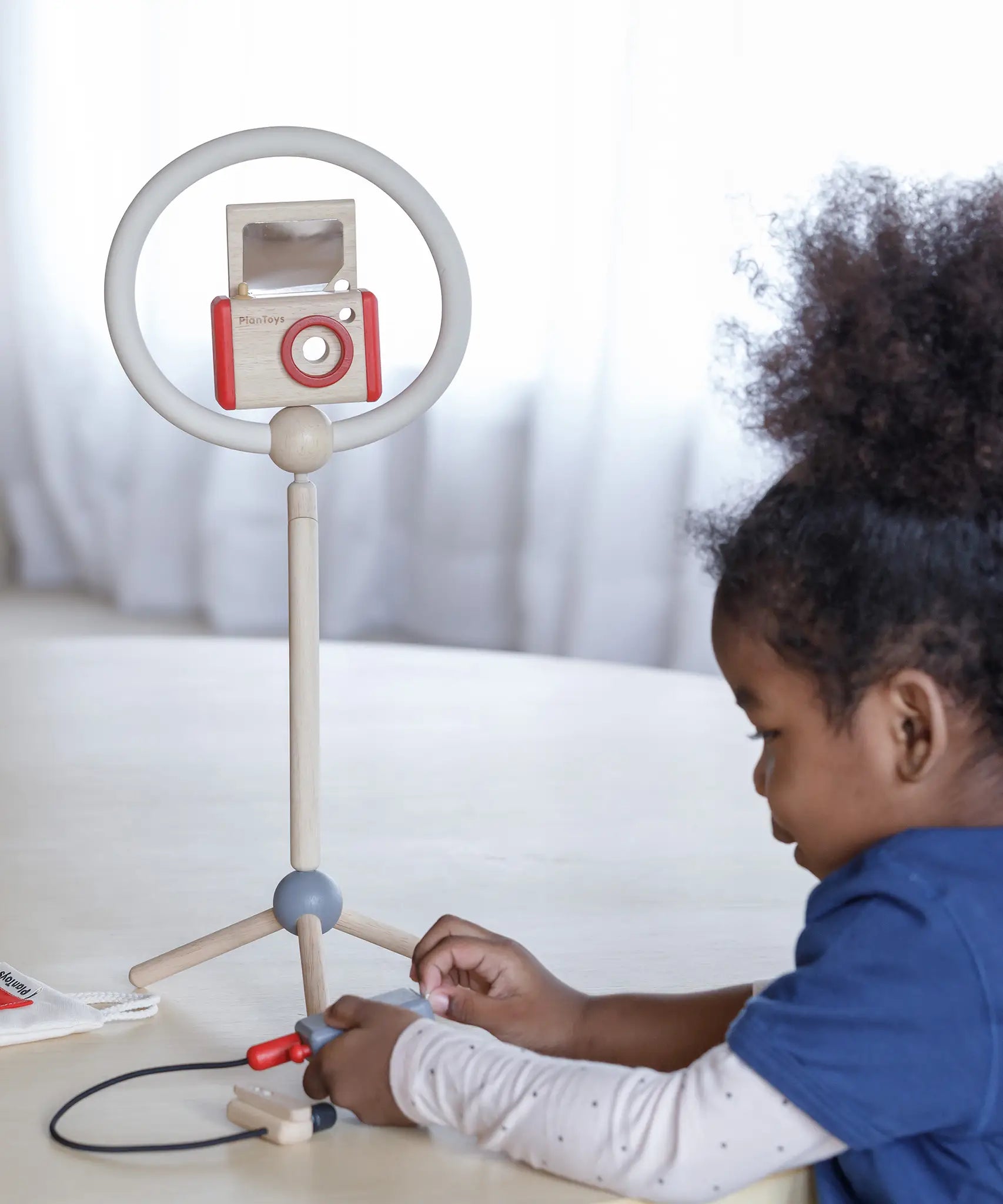 Child setting up the ring light and camera from the PlanToys pretend vlogger kit