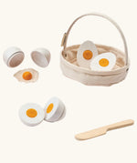 PlanToys crack & cook egg basket set. Showing 3 different types of white eggs to cut and a wooden knife