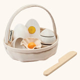 PlanToys crack & cook egg basket set. Showing 3 eggs inside the carry basket next to a wooden knife