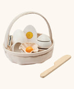 PlanToys crack & cook egg basket set. Showing 3 eggs inside the carry basket next to a wooden knife