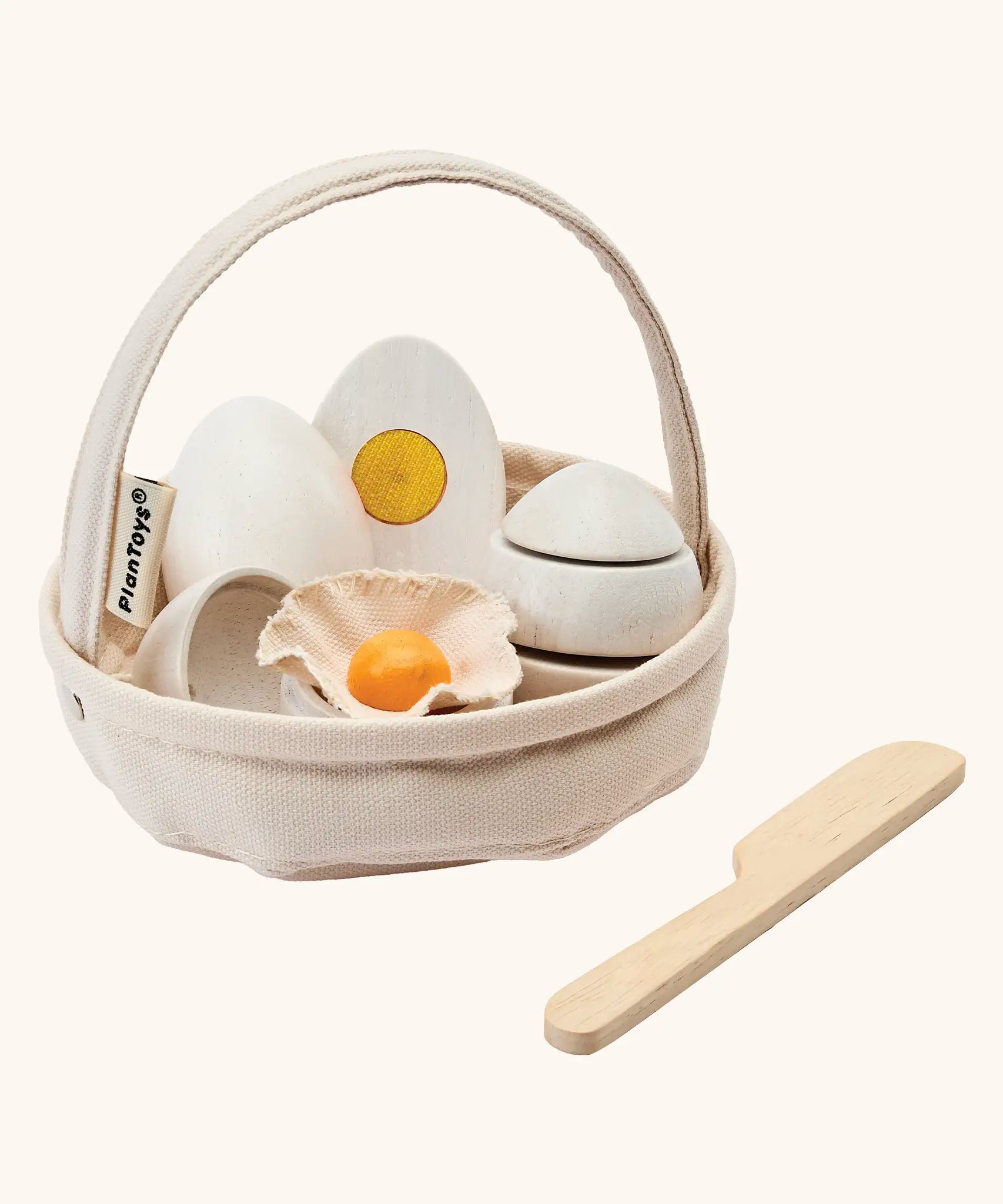 PlanToys crack & cook egg basket set. Showing 3 eggs inside the carry basket next to a wooden knife