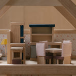 A side on view of the pieces from the PlanToys Dining Room Dolls House Furniture set set up in a wooden dolls house. 