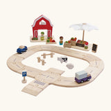 PlanToys wooden roadway with farm animals in the middle. Showing the market and farm set standing behind