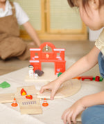 Child assembling loose wooden road pieces from the PlanToys fire & rescue roadway set.