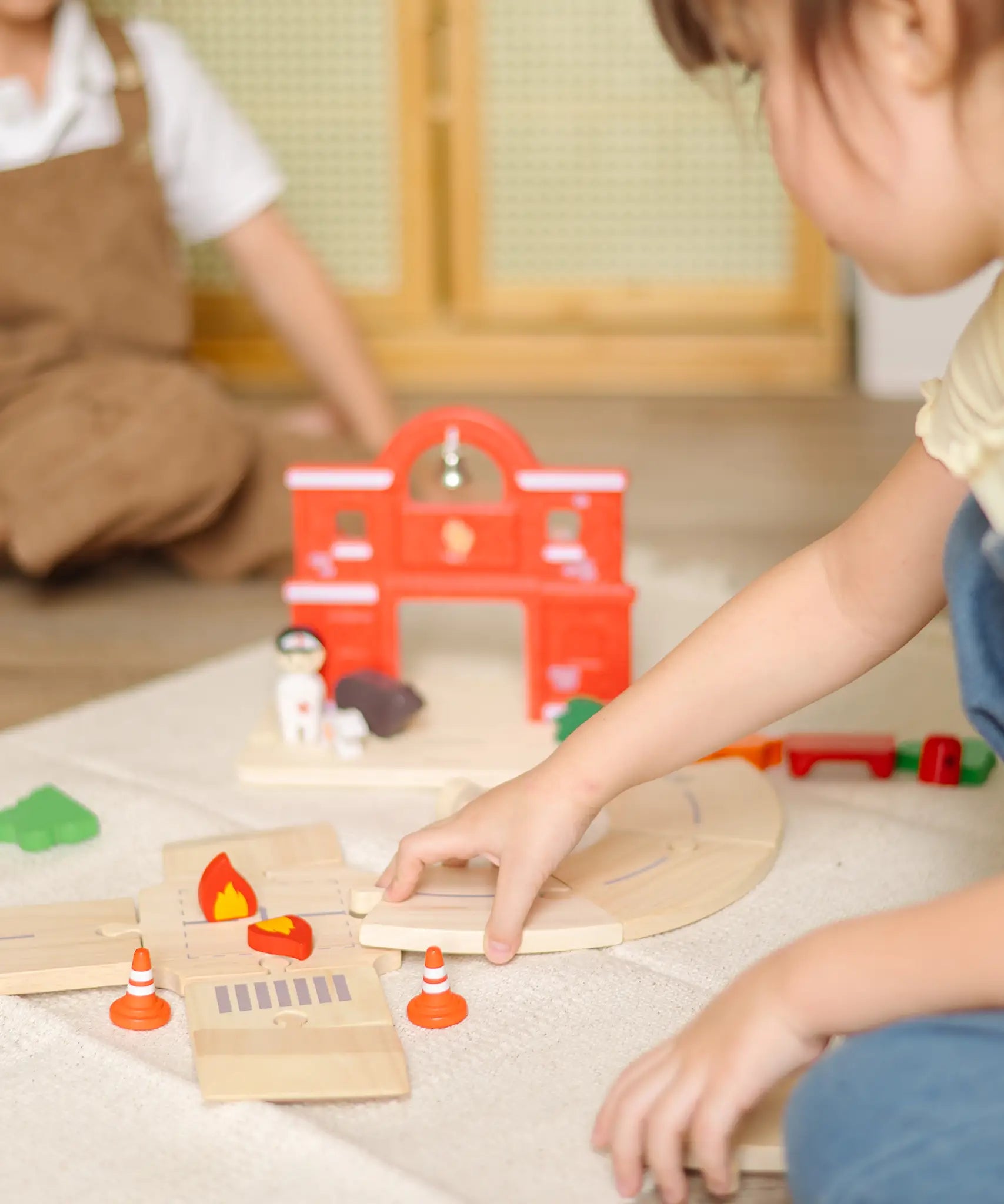 Child assembling loose wooden road pieces from the PlanToys fire & rescue roadway set.